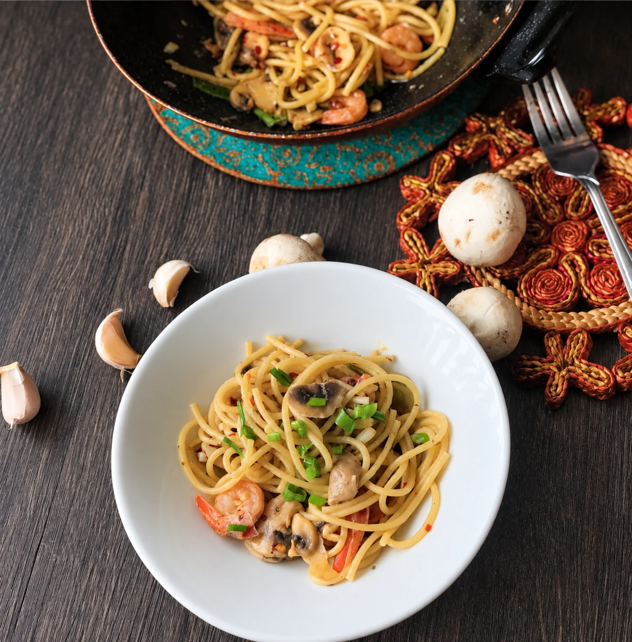 Buttery garlic shrimp scampi spaghetti with sliced mushrooms and green onions in a white bowl